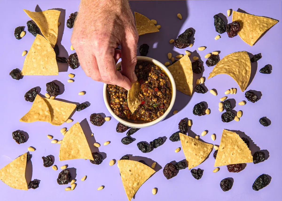 Chips and salsa on lilac with a hand reaching in