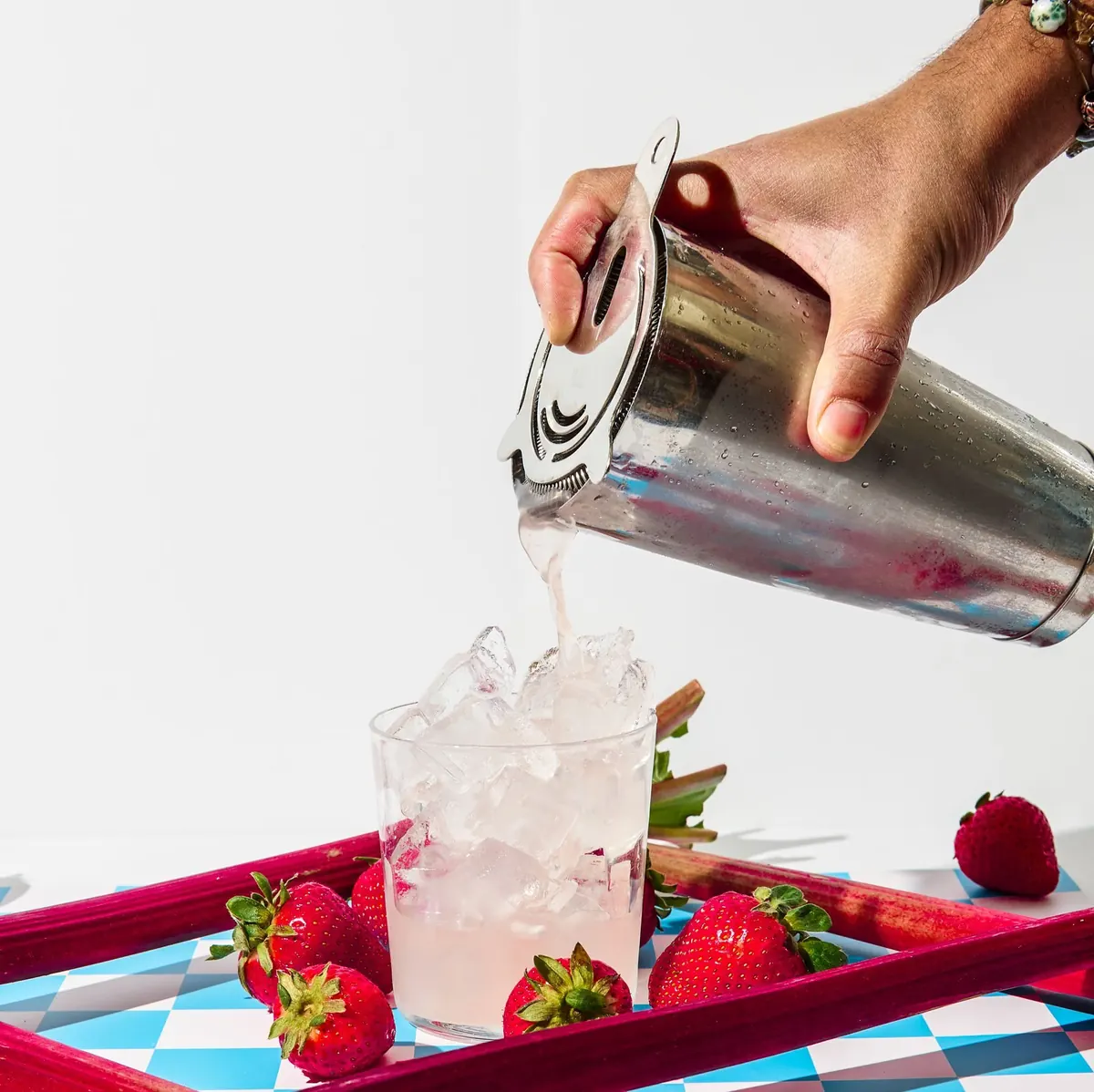 Drink poured over ice on a checkerboard tray with strawberries