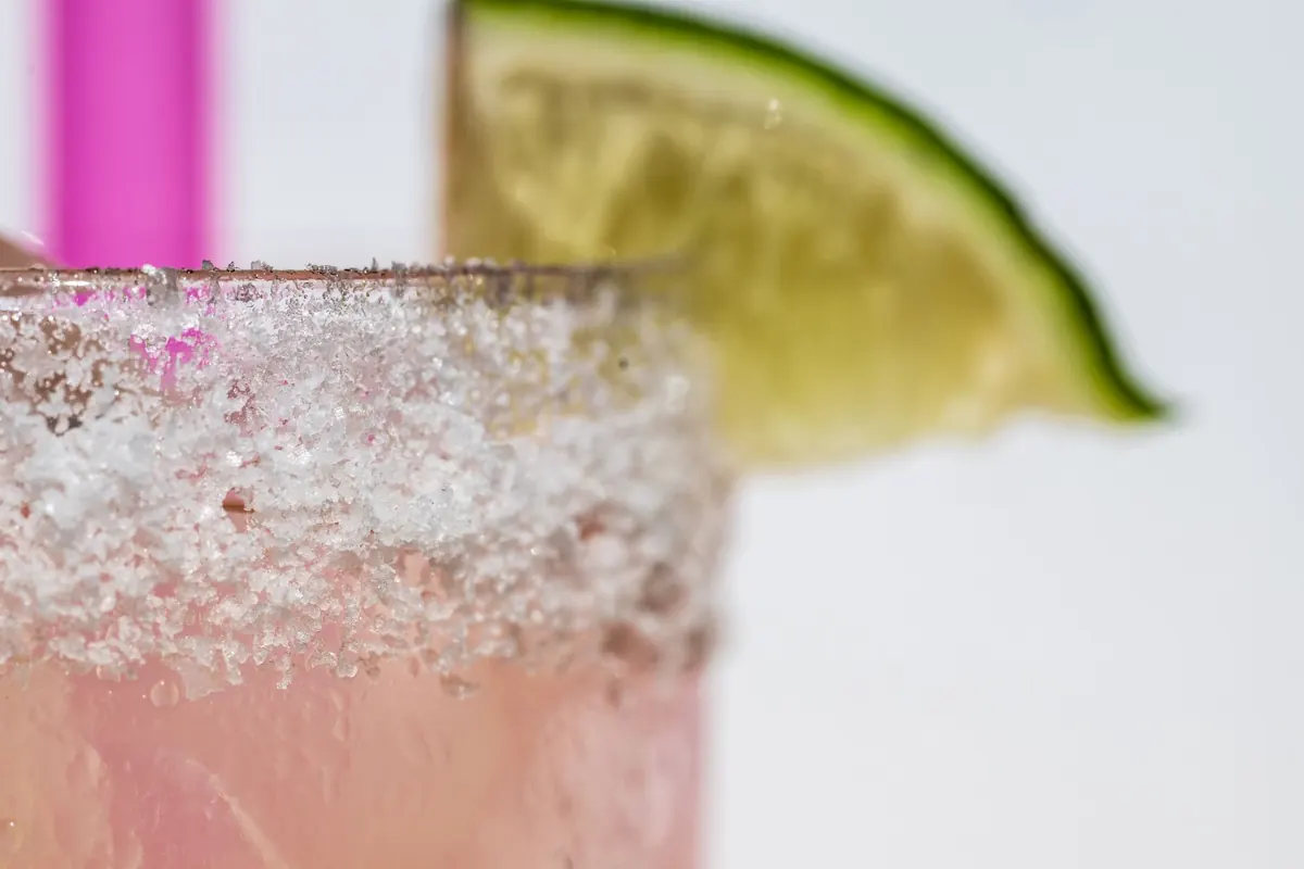 Salt-rimmed pink margarita with a lime wedge