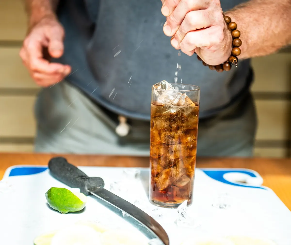 Soda poured over ice with a knife and lime on the board