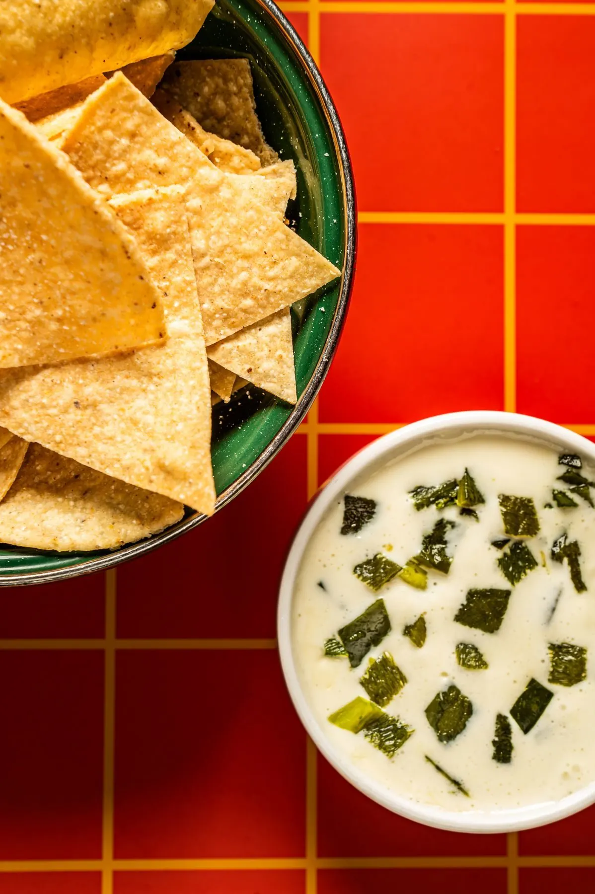 Tortilla chips and crema from overhead on an orange grid